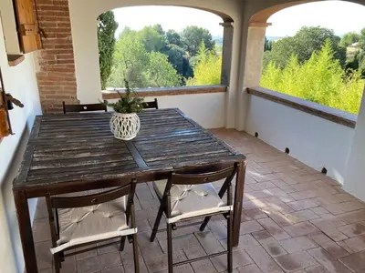 a wooden table and chairs in a room with two windows at Habitación suite en Masía Can Robira in Els Hostalets
