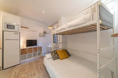 a bedroom with two bunk beds and a kitchen at Welcomy Sant Andreu in Barcelona