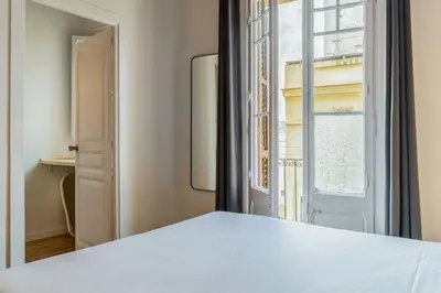 a bedroom with a white bed and a mirror at Canela Homes BARCELONA CÒRSEGA in Barcelona