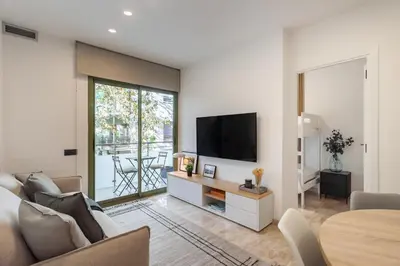 a living room with a couch and a tv on a wall at Cozy Apartment Les Corts in Barcelona