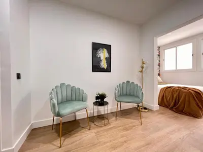 two chairs in a bedroom with a bed and a window at Crysoyle Apartment Barcelona Next to Camp Nou in Hospitalet de Llobregat