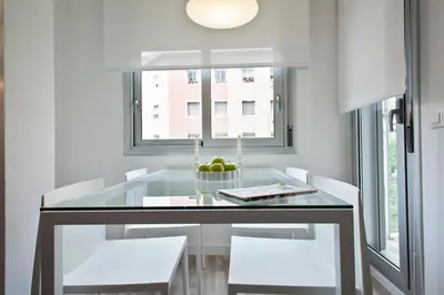 a dining room with a glass table and white chairs at Habitat Apartments Blanca in Barcelona