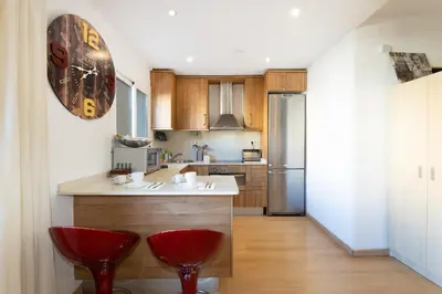 a kitchen with a counter and two red chairs at Cute Apartment in Sants Station with HBO & Alexa & AC in Barcelona