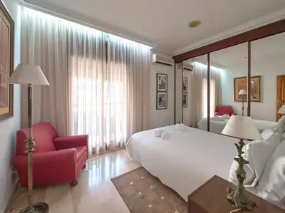 a bedroom with a large white bed and a red chair at Stay U-nique House Torre Damians in Barcelona