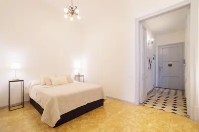 a white bedroom with a bed and a chandelier at Rafael Music Palace apartment in Barcelona