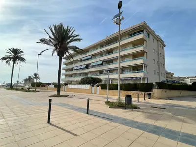 a large building with a palm tree in front of it at Cunit Beach in Cunit