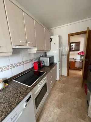 a small kitchen with white cabinets and a sink at Cunit Beach in Cunit