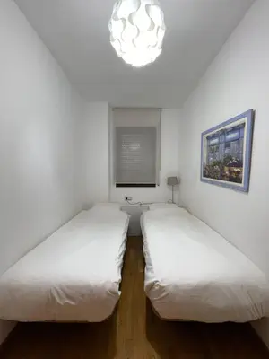 two beds in a white room with a chandelier at Comfy Downtown + Private terrace in Barcelona