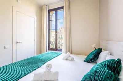 a bedroom with a large white bed with green pillows at The Collection Barcelona - Eixample next to Paseo de Gracia modern 3BD in Barcelona