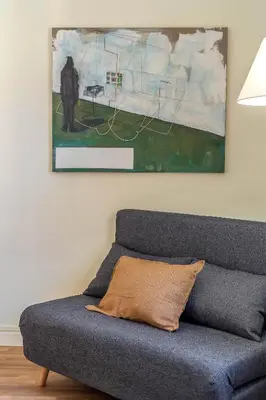 a couch in a living room with a painting on the wall at Canela Homes BARCELONA MODERNISTA in Barcelona