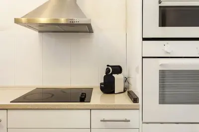 a kitchen with white cabinets and a stove top oven at Canela Homes BARCELONA RAMBLA CAT in Barcelona