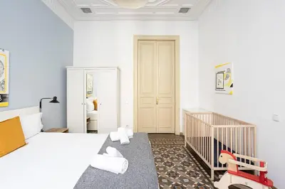 a white bedroom with a crib and a room with white walls at Canela Homes BARCELONA CONSELL in Barcelona
