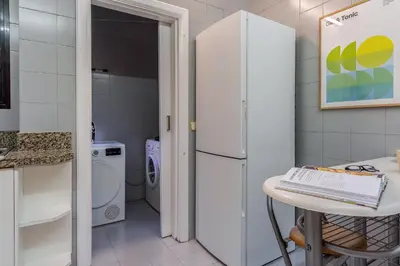 a kitchen with a white refrigerator and a table at Canela Homes BARCELONA NINOT in Barcelona