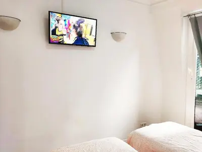 a television hanging on a white wall in a bedroom at Fira Suites in Barcelona