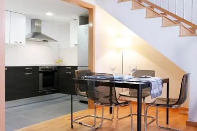 a kitchen with a black table and chairs and a staircase at Fira Duplex in Hospitalet de Llobregat