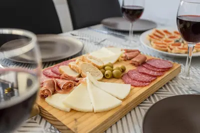 a plate of cheese and meats on a table with glasses of wine at Canela Homes BARCELONA FONTANA in Barcelona
