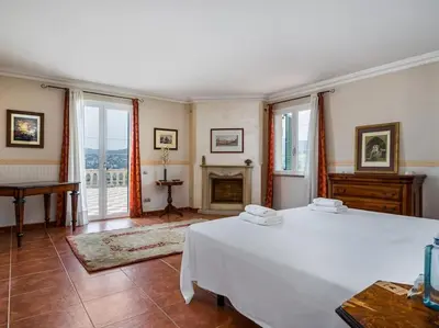 a bedroom with a large white bed and a fireplace at Architectural jewel between sea and mountains in Teià