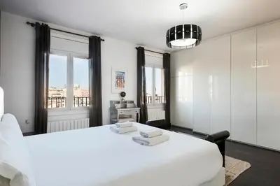 a white bedroom with a large white bed and windows at Stay U-nique Apartments Rambla Catalunya IV in Barcelona