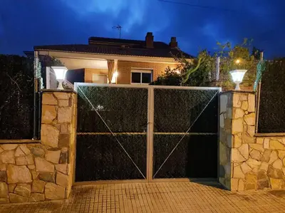 a gate in front of a house at night at Casa con jardín y piscina privada. in Santa Eulalia de Ronsaná
