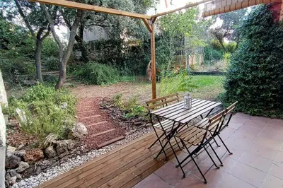 a wooden table and chairs under an umbrella on a patio at Casa de invitados in La Torre de Claramunt