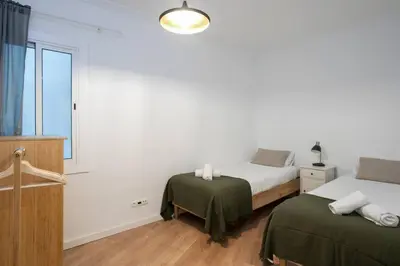 a white bedroom with two beds and a window at Canela Homes BARCELONA PADILLA in Barcelona