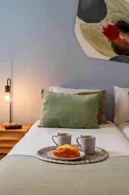a tray with two cups and a plate of food on a bed at Canela Homes BARCELONA FIRA in Barcelona
