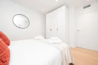 a white bedroom with a bed and a mirror at Soler Apartments in Sant Adria de Besos