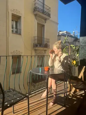 a woman sitting at a table on a balcony eating at Stunning Designer 2 Bed Apt in Glorious Gràcia in Barcelona