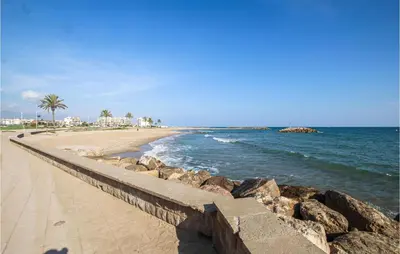 a beach with a retaining wall next to the ocean at 4 Bedroom Lovely Apartment In Cunit in Cunit