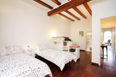 a white bedroom with two beds and a table at FANTASTIC apartment in Barcelona in Barcelona