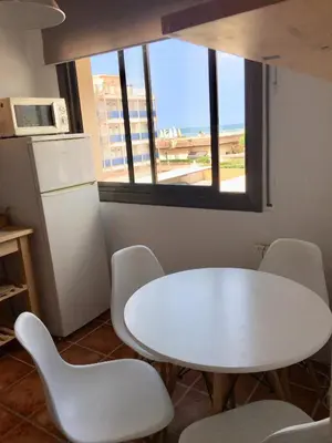 a white table and chairs in a kitchen with a window at Beach Castelldefels in Castelldefels