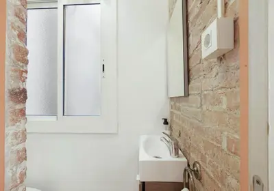 a bathroom with a white sink and a brick wall at Great apartment in Sagrada Familia with Balcony in Barcelona