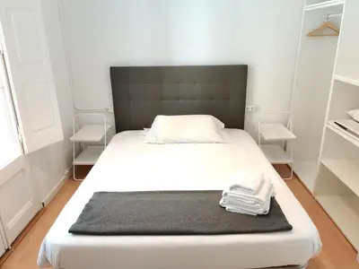 a bedroom with a white bed with a black headboard at Family apartment Gracia in Barcelona