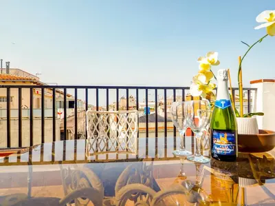 a table with a bottle of wine and glasses on a balcony at Sea and Sand Penthouse by Hello Homes Sitges in Sitges