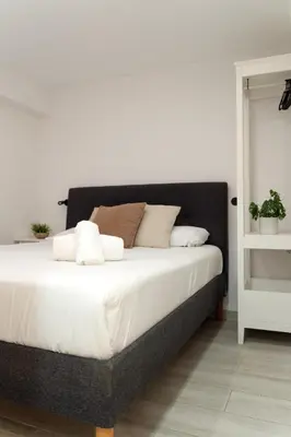 a bedroom with a large bed with white sheets at Refugio playero para 5 personas in Castelldefels