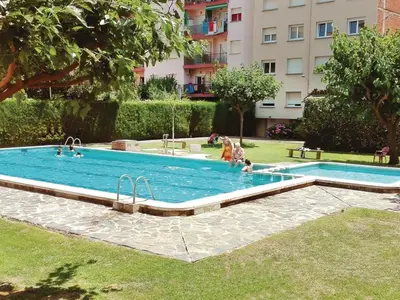 a swimming pool in a park with people in it at Apartamento con vistas al mar y piscina in Pineda de Mar