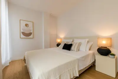 a white bedroom with a large white bed with two lamps at CATERINA Editorial in Barcelona