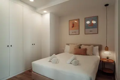 a bedroom with a white bed with two pillows on it at CATERINA Liceu in Barcelona