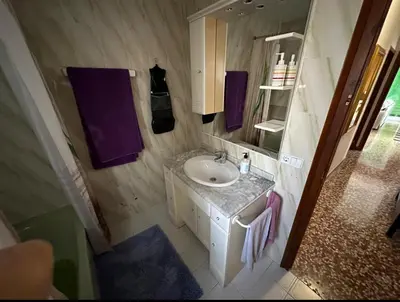a bathroom with a sink and a mirror and purple towels at Piso superior tranquilo terraza y vistas A 45 min de Barcelona in Cunit