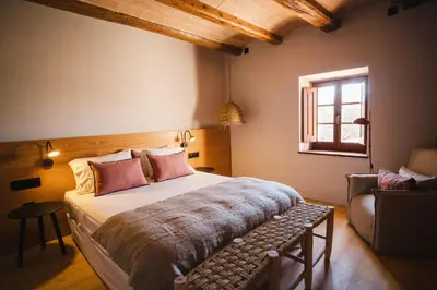 a bedroom with a bed and a chair and a window at Hotel-Masia Can Farrés in El Bruc