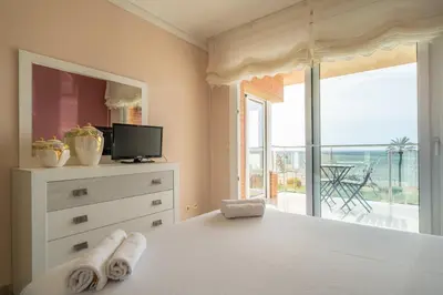 a bedroom with a white bed with a view of the ocean at HomeHolidaysRentals Noelani- Costa Barcelona in Pineda de Mar
