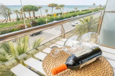 a glass table with a bottle of wine on a balcony at HomeHolidaysRentals Noelani- Costa Barcelona in Pineda de Mar
