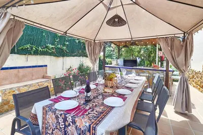 a long table with chairs and a large umbrella at Villa ilusions en Olivella, Sitges, Barcelona in Olivella
