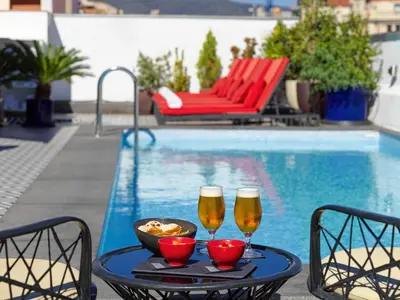 two glasses of beer on a table next to a pool at H10 Metropolitan 4* Sup in Barcelona