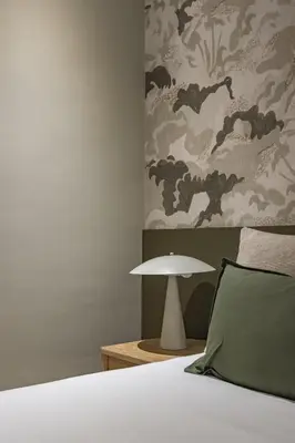 a bedroom with a bed and a lamp next to a wall at Ola Living Hostal Diagonal in Barcelona