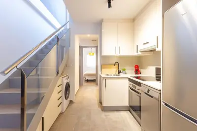 a kitchen with white cabinets and a staircase at Duplex with terrace near Bcn in Terrassa