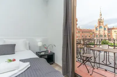 a bedroom with a balcony with a bed and a table at Housalia Sant Pau Views- Suite with View on Hospital Sant Pau in Barcelona