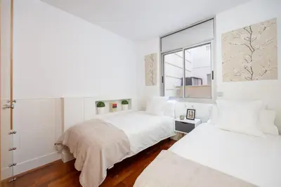 two beds in a white room with a window at Marion House Barcelona in Barcelona