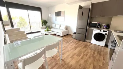 a kitchen and living room with a table and a couch at Dúplex con terraza by Prestigi in Terrassa