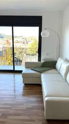 a living room with a couch and a large window at Dúplex con terraza by Prestigi in Terrassa
